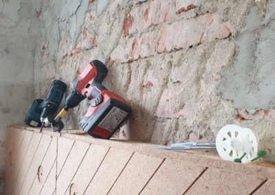 Holzfaser-Dämmplatte UdiIN RECO an der Wand montiert, auf der Platte liegen Dübel und Werkzeug